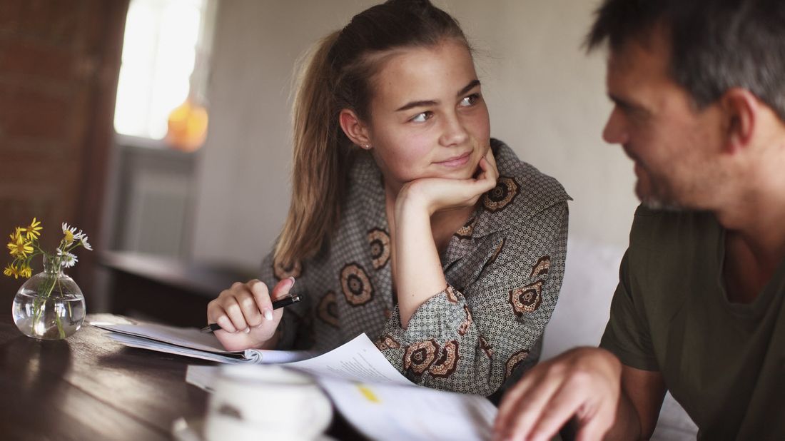 Dad at a table asking his daughter financial questions before they decide on a college
