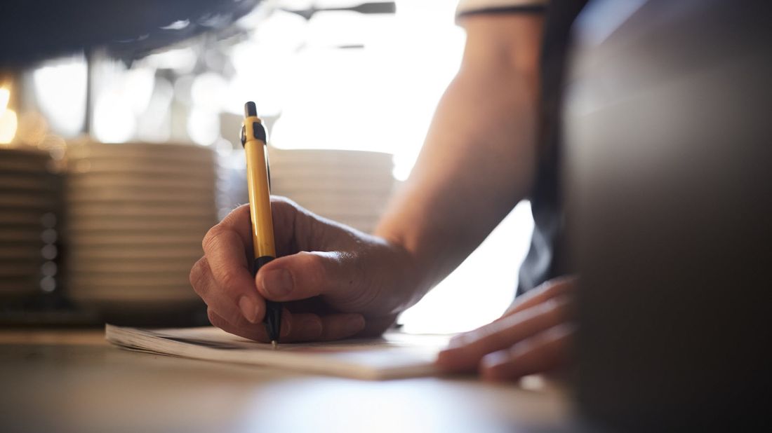 Woman writing checklist as she prepares to return to work after a disability.