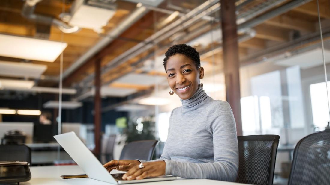 Woman smiling at camera and using laptop