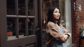 Woman standing outside of work smiling as she thinks about how to open a Roth IRA.