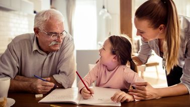 An elderly parent helps graddaughter with her homework