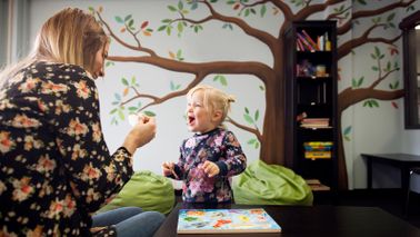 nanny playing with small child in playroom