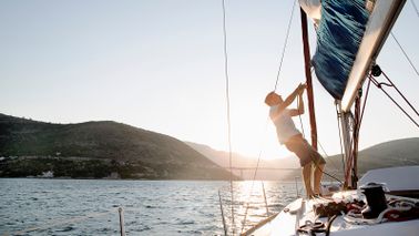 man hoisting sail on boat