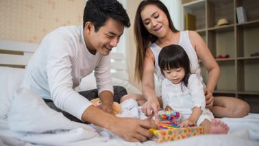 parents-with-child-tax-credits-playing-game-with-daughter-on-bed