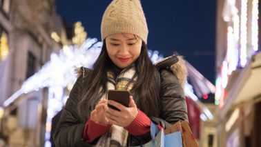 Woman checking her smartphone while doing holiday shopping