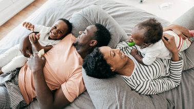 Couple lying on a bed with their kids