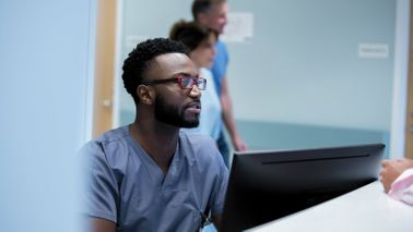 Doctor working at a computer and researching disability insurance for physicians.