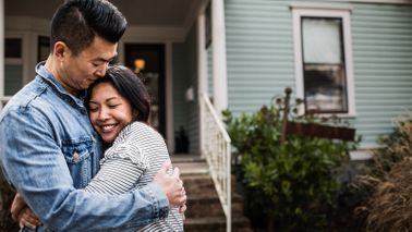 Young couple hugging in front of new home