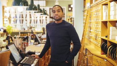 A young business owner behind the counter at his shop