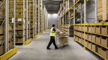 A warehouse worker at risk of automation moves goods on cart
