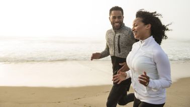Man and woman jogging side by side on beach