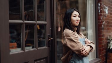 Woman standing outside of work smiling as she thinks about how to open a Roth IRA.