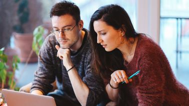 Young couple reading Northwestern Mutual’s Weekly Market Commentary amid current market volatility.