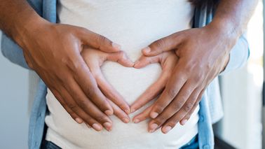 couples' hands on pregnant belly