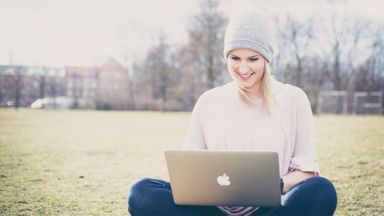 Woman on her laptop outside paying down debts