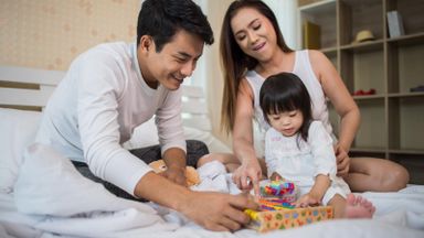 parents-with-child-tax-credits-playing-game-with-daughter-on-bed