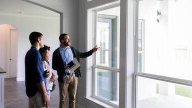 Couple who needs a mortgage lender looking at a home with real estate agent