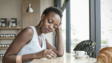 Woman sitting at a table and drinking coffee while learning about the basics of investing