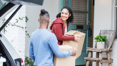 Couple carrying boxes into new house