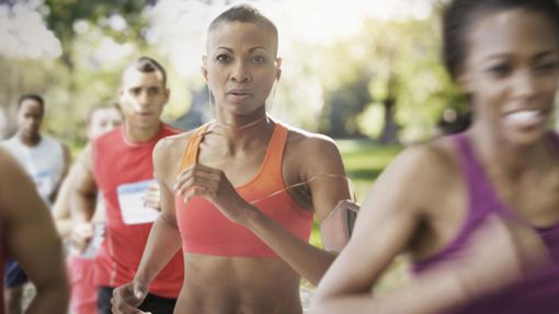 Woman running in a competitive race while listening to music.